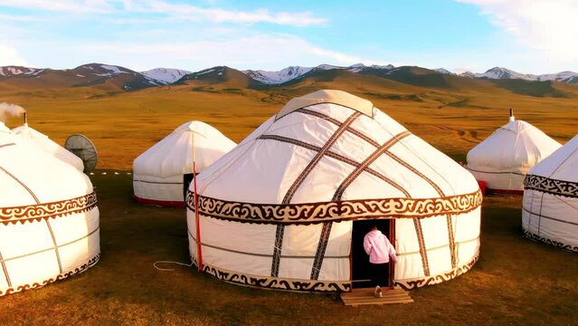 Nomadic yurt camp and snowy mountains on a meadow