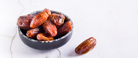 Ripe dried dates in a bowl on the table. Oriental dessert. Web banner