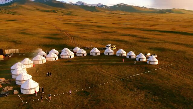 Nomadic yurt camp and snowy mountains on a meadow