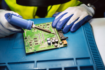 Electrician technician using hot soldering iron to fix repair small electrical digital computer...