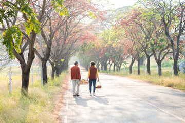 Father and daughter walking on country road with fall color from maple tree during autumn season...