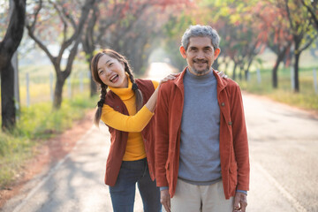 Happy woman enjoying with father on country road with maple tree during autumn season