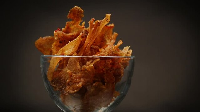 dried meat with spices in a glass bowl, isolated on black background