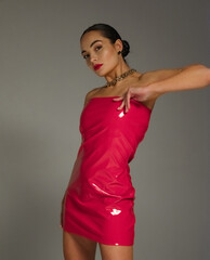 Young pretty brunette woman poses in stylish red latex dress and chain in her neck.