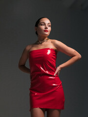 Young pretty brunette woman poses in stylish red latex dress and chain in her neck.