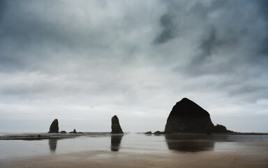 Haystack Rock Reflects In The Low Tide Of Canon Beach On Cloudy Morning