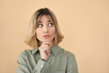 Cute curious blonde get z girl holding hand on chin looking interested aside isolated on beige...
