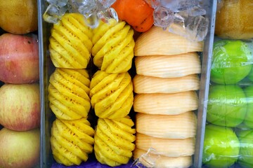 A mix fruits in the glass cabinet chilled on the cart for sale at local market.