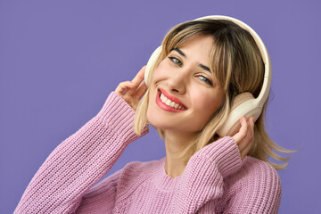 Cool smiling teen girl, happy funky gen z blonde young woman wearing pink sweater and headphones...