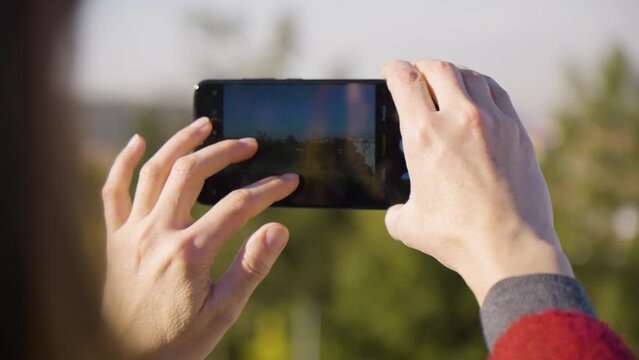 A woman takes pictures of a landscape and cityscape with a smartphone - rear closeup