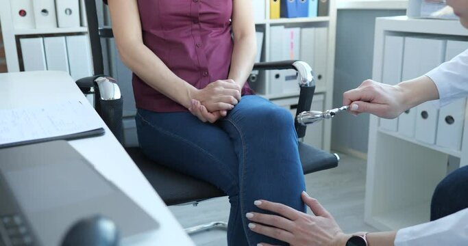 Neurologist checks reflexes on woman's knee with hammer. Diagnostics of nervous system concept