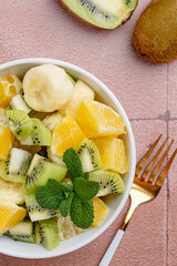 Bowl of healthy fresh fruit salad on ceramic background