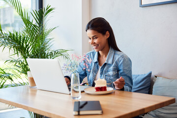 Woman eating cafe using laptop at cafe