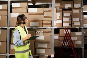 Portrait of a smiling warehouse staff using a headset while working in a distribution warehouse....