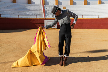 Hispanic matador dancing on sandy arena