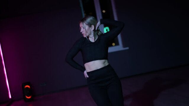Live camera. Dancing woman in a choreographic hall with neon lighting. Active waving of the arms and gestures while performing the dance