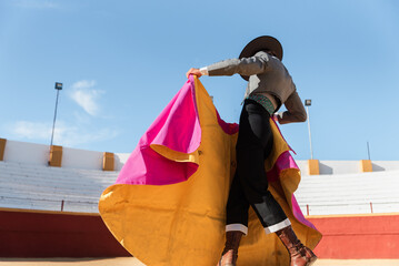 Hispanic matador dancing on sandy arena - obrazy, fototapety, plakaty