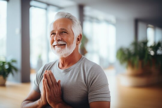 Elderly man studying yoga class on his own in gym