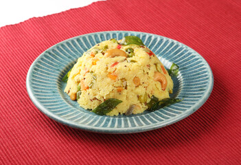 Upma made of samolina or rava upma, most famous south indian breakfast item which is arranged in a black plate and garnished with fried cashew nut and curry leaves 