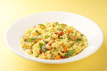Upma made of samolina or rava upma, most famous south indian breakfast item which is arranged in a black plate and garnished with fried cashew nut and curry leaves 
