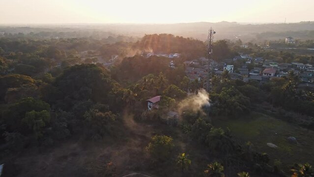 An aerial view of Mandwa Village at sunrise showcases houses surrounded by coconut trees that enhance the village's natural beauty.
