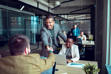 Smiling businessman shaking hand with colleague in office