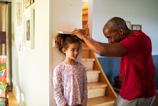 Father Measuring Height Of Daughter At Home