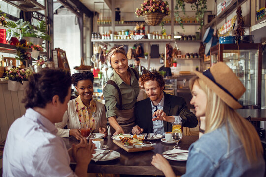 Waitress serving food for customers at restaurant