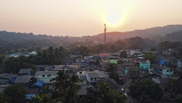 An aerial view of Mandwa Village at sunrise showcases houses surrounded by coconut trees that enhance the village's natural beauty.