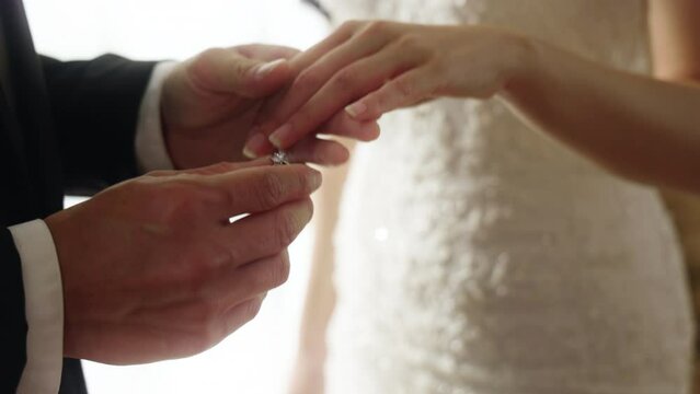 Close up of groom putting wedding ring on bride's finger during ceremony
