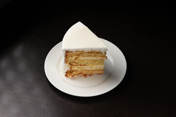 A piece of white cake with marzipan under dark lighting. Close-up	