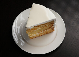 A piece of white cake with marzipan under dark lighting. Close-up