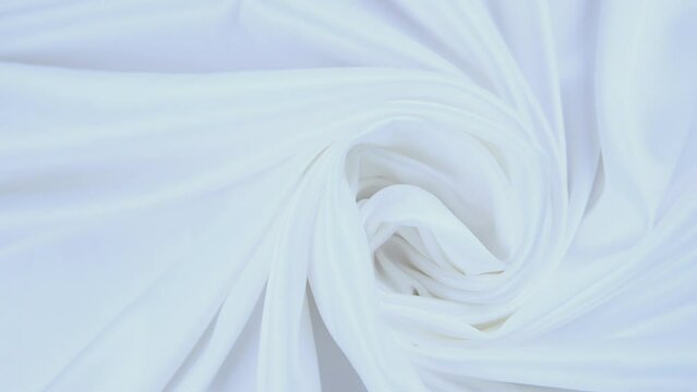 Shiny white flowing cloth texture shot in close up view macro shot. Wavy clean silk weave material. Textile satin abstract background. Bed sheet, curtain and clothing industry concept.