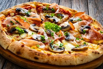 Fototapeten Pizza speck with ham, mozzarella cheese and white mushrooms on wooden table  © Jacek Chabraszewski