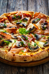 Pizza speck with ham, mozzarella cheese and white mushrooms on wooden table
