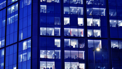 Fragment of the glass facade of a modern corporate building at night. Big glowing windows in modern...