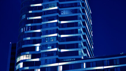 Fragment of the glass facade of a modern corporate building at night. Big glowing windows in modern...