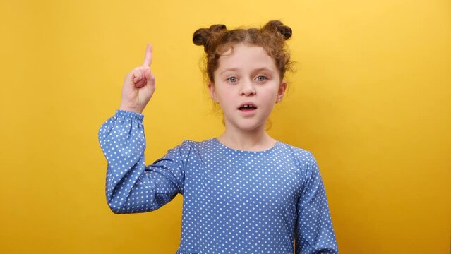 Idea concept. Portrait of inspired little girl kid with open mouth pointing finger up in inspiration, having solution for problem, posing isolated over plain yellow color background wall in studio