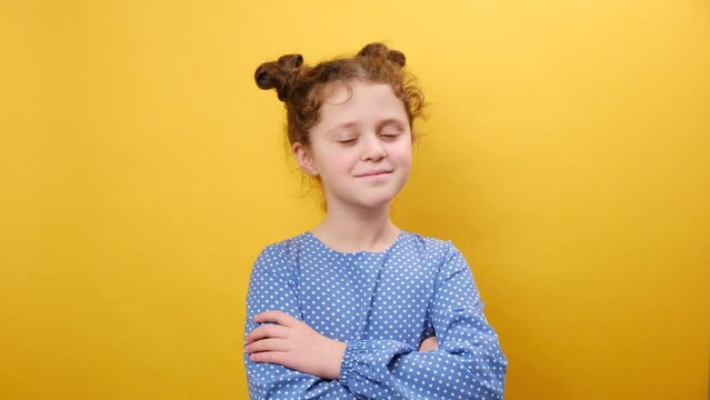 Approval and good concept. Portrait of cool preteen caucasian girl crossing hands and nodding head, expressing ok and agreement, posing isolated over plain yellow color background wall in studio