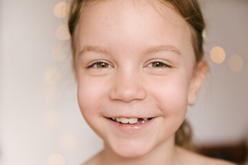 A large portrait of a girl, happy and staring into the camera, a smile without a tooth. The concept of milk tooth loss