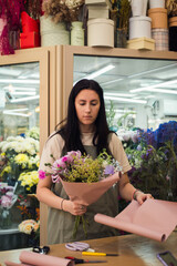 young woman florist making bouquet fresh flowers, flower shop business