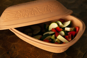 Traditional Roman pot made of clay, filled with raw vegetables ready to bake. Healthy cooking with ancient historic pot.