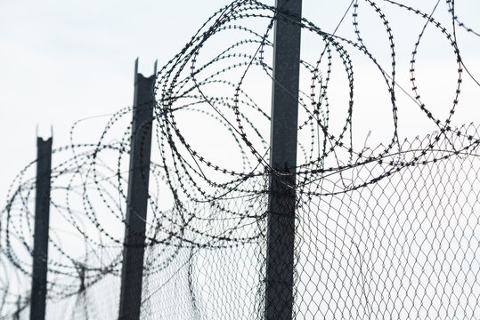 Fence with barbed wire. Dangerous fence. Intrusion protection. Barbed wire on the border.