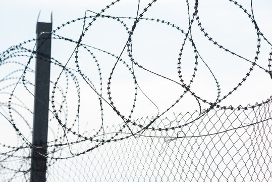 Fence with barbed wire. Dangerous fence. Intrusion protection. Barbed wire on the border.