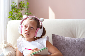A girl of European appearance wearing headphones at home is studying online. Selective Focus, Horizontal Image