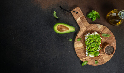 Delicious wholewheat toast with avocado, cream cheese and chia seeds on a wooden board. top view....