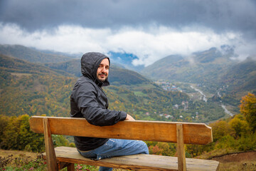 Traveler Relaxing on Wooden Bench at Observation Point, Admiring Spectacular Mountain Scenery