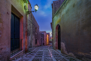 A characteristic alley of the Erice medieval town at nightfall, Sicily - 690751216