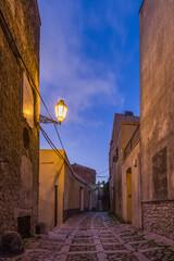 A characteristic alley of the Erice medieval town at nightfall, Sicily - 690751260