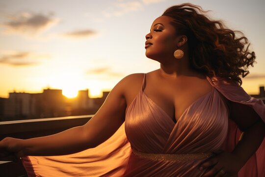 young plus-size Afro-American woman dancing on a rooftop at sunset